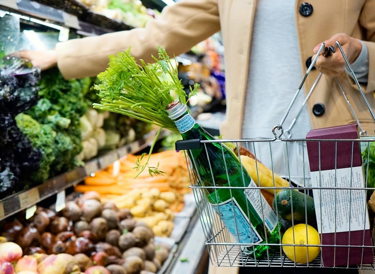 woman holding a grocery basket shopping for healthy produce for skin health